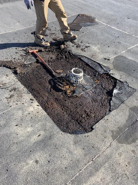 Flat roof cut open around a roof drain for a leak repair