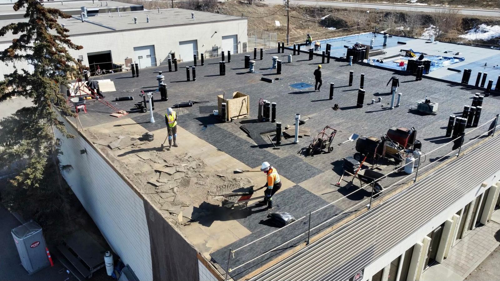 Crew re-roofing a warehouse flat roof, seen from above