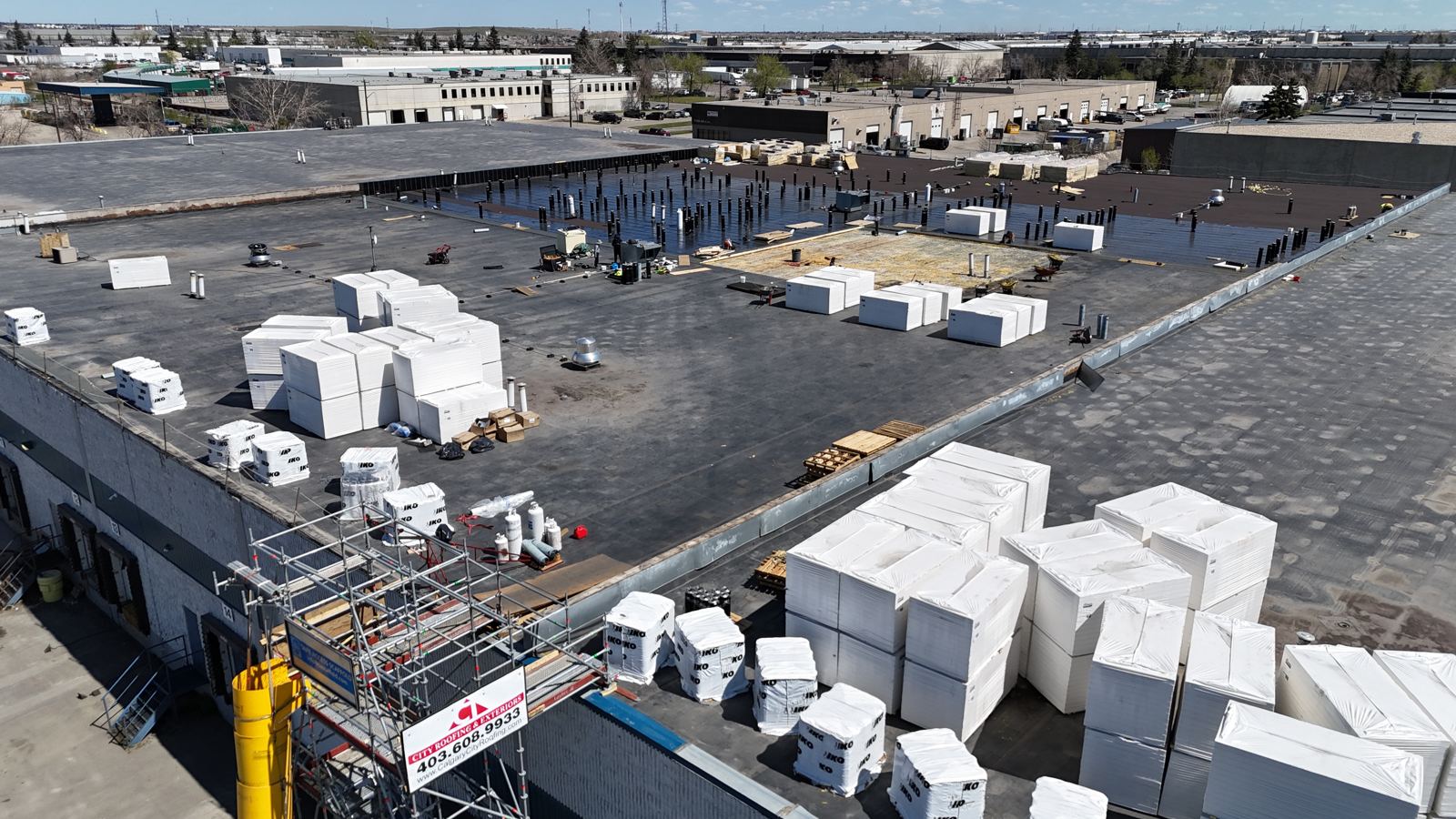 Warehouse roof mid tear-off with new insulation staged on the deck