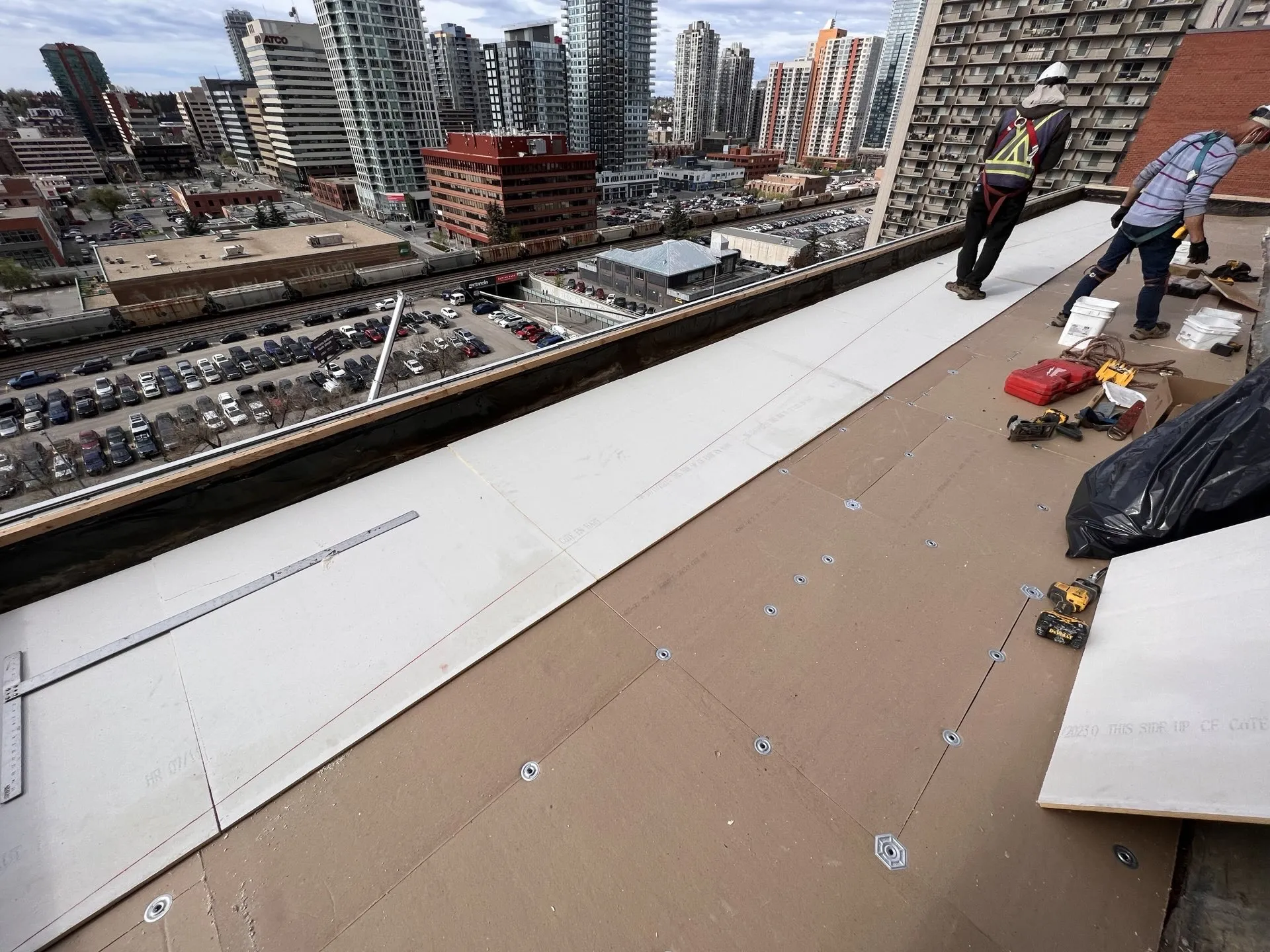 Roofing crew working on a rooftop with downtown Calgary towers behind