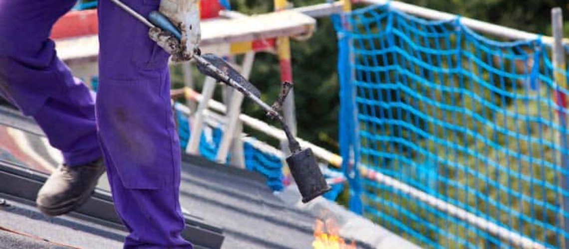 roofer working on tar paper with fire